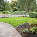Lawn and curved garden bed with plants and mulch