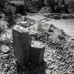 pillar stone water feature next to grey stones and paver patio