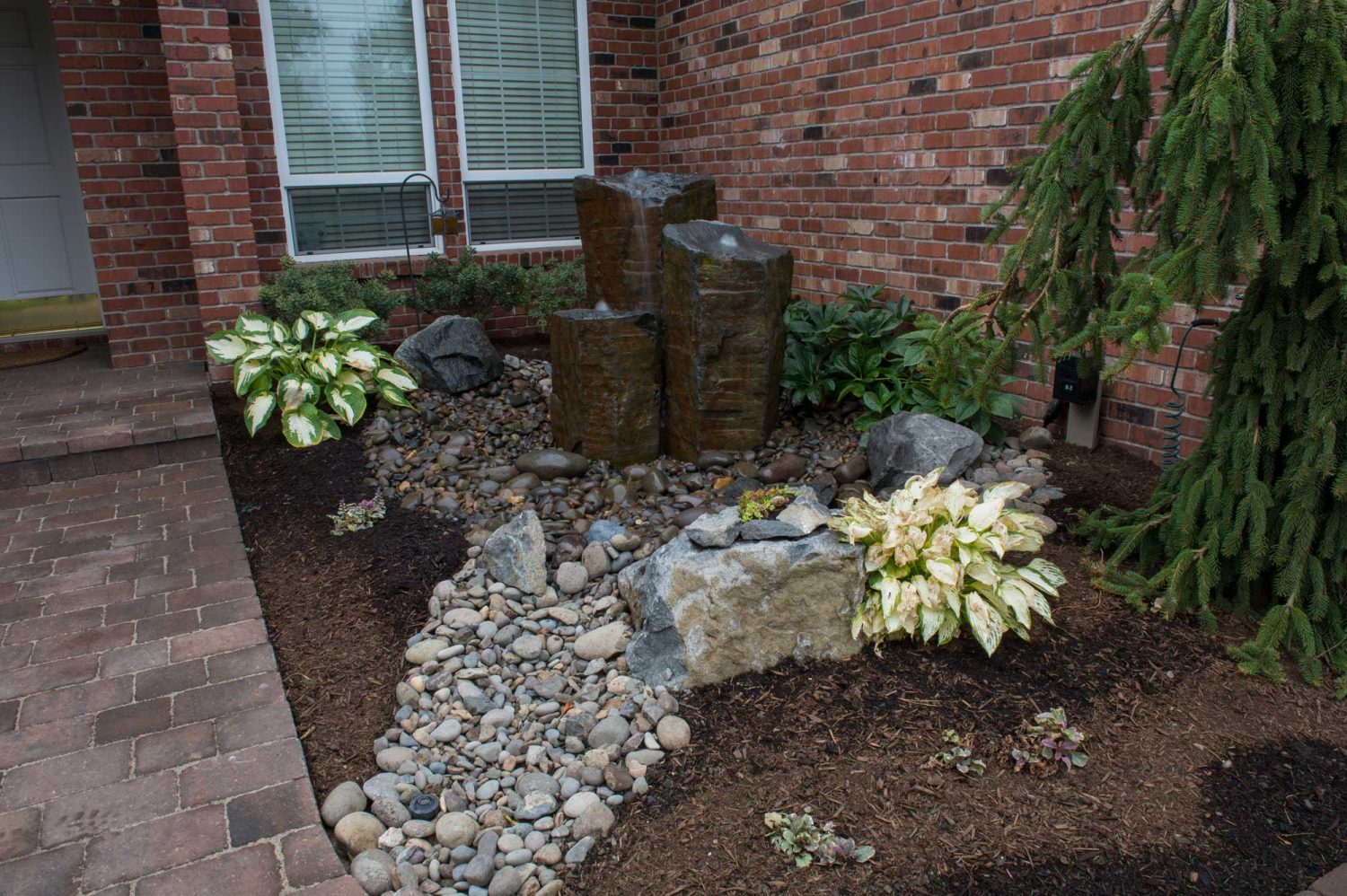 natural water feature with stone and rocks in front of the house.